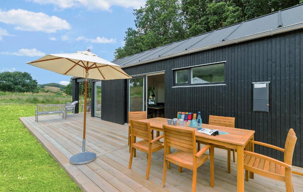 a wooden deck with a table and an umbrella at 4 Bedroom Nice Home In Ebeltoft in Ebeltoft