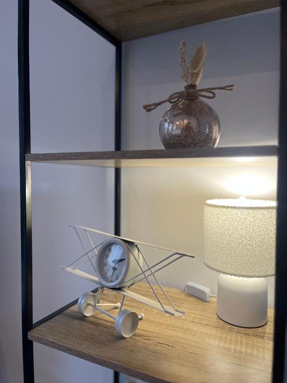 une étagère avec une horloge et une lampe sur elle dans l'établissement Écrin des nuages, à Cognac