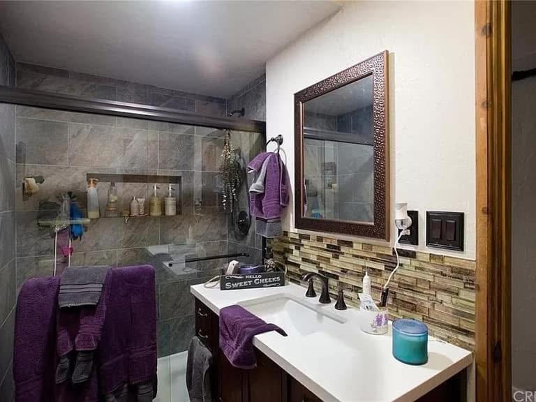 y baño con lavabo y ducha con toallas púrpuras. en Sandalwood, en Pine Mountain Club