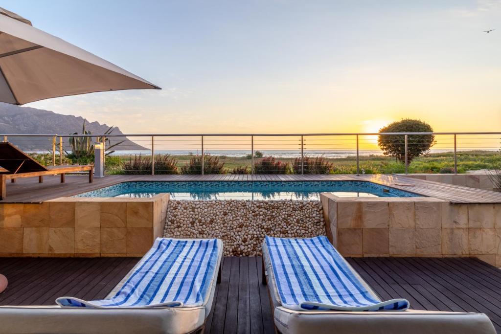 una piscina con dos tumbonas y una sombrilla en "Villa Montemar' Luxury Villa for 6 on the Beach with Pool, en Gordonʼs Bay