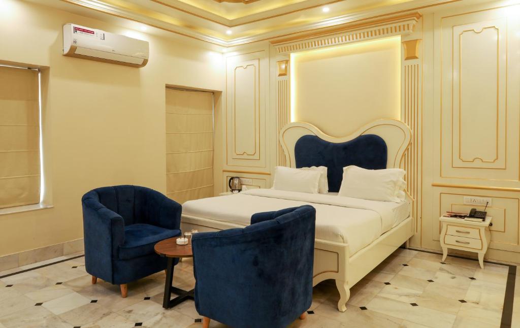 a bedroom with a bed and two blue chairs at HOTEL CITY PALACE in Bikaner