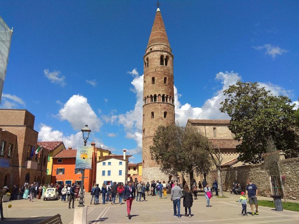 Un gruppo di persone che camminano davanti a una torre alta di Meridiana, 2 Bedrooms a Caorle