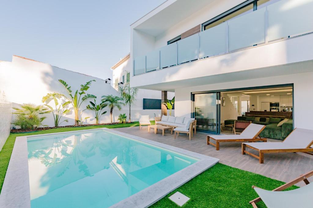 eine Außenansicht eines Hauses mit Swimmingpool in der Unterkunft Botánica by Caparica Experience in Charneca