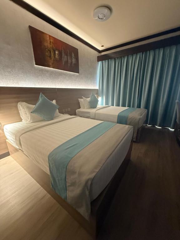 a hotel room with two beds and a window at Strand Hotel in Abu Dhabi