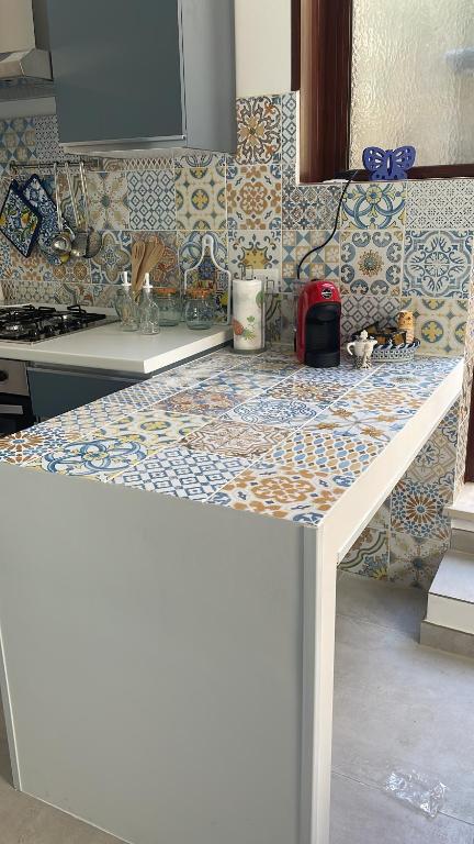 a kitchen with a counter top with a tile wall at Angú - Casa Vacanze in Avola