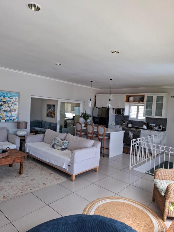 a living room with white furniture and a kitchen at Rising Tide in Fish hoek