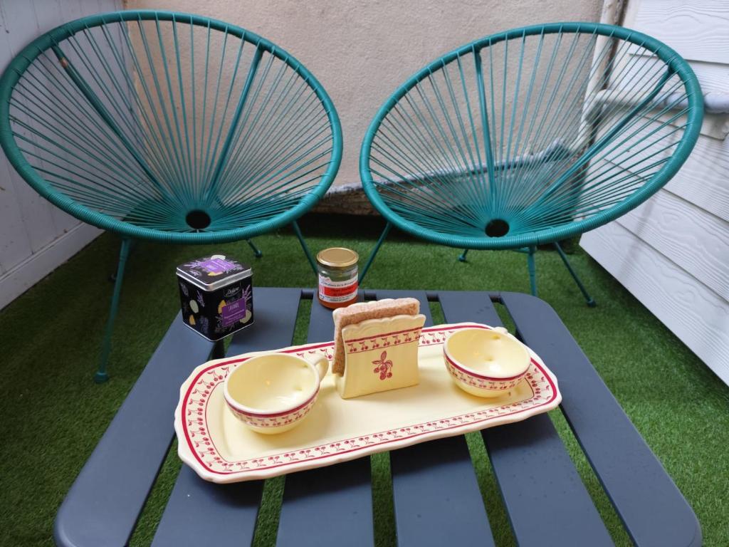 - une table de pique-nique avec une assiette de nourriture et 2 chaises dans l'établissement appartement la place, à Eaux-Bonnes