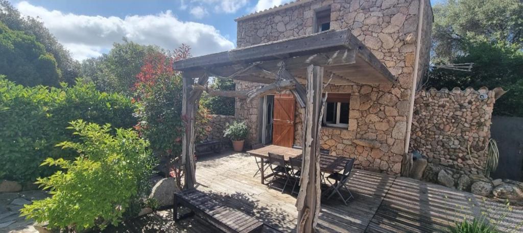 una casa con terrazza in legno e tavolo di Cottage bergerie en pierres avec jacuzzi en corse 6 personnes, 3 chambres a Coti-Chiavari