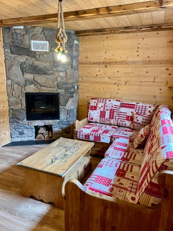 Cette cabane en rondins comprend un canapé, une table et une cheminée. dans l'établissement Gîte 2 à 8 personnes style chalet avec garage privé et jardin, à La Bresse