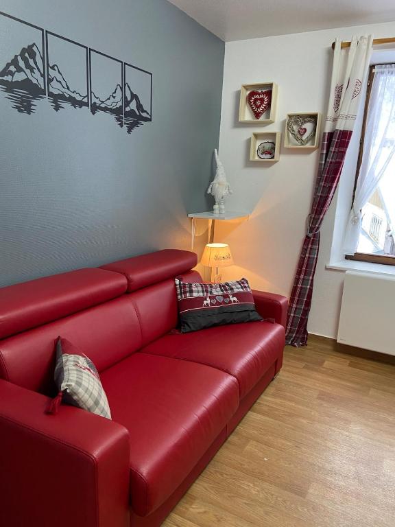 - un canapé en cuir rouge dans le salon dans l'établissement Appartement F2 La Bresse, à La Bresse