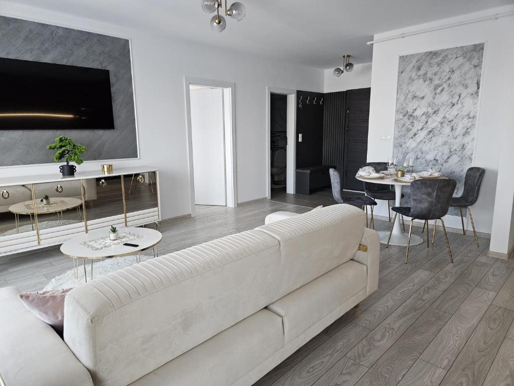 ein Wohnzimmer mit einer weißen Couch und einem Tisch in der Unterkunft Milan Luxury Apartaments VIII #Târgu Mureș in Târgu Mureș