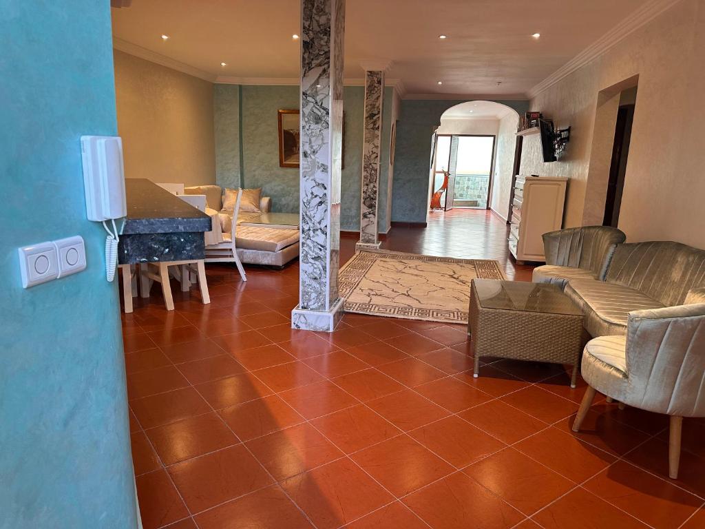 a living room with a tiled floor with chairs and a table at Hotel L'Initiale in Oualidia