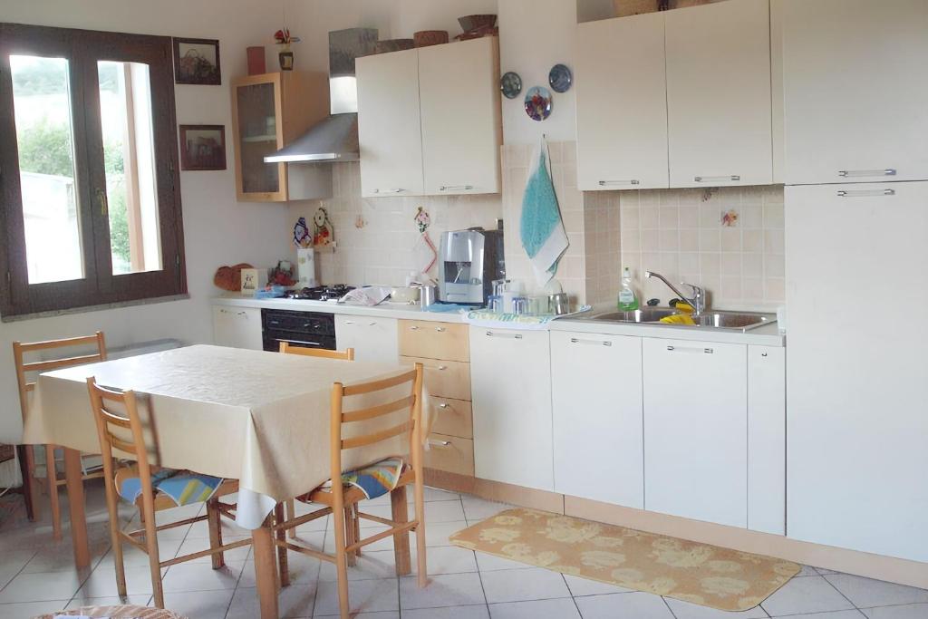 kuchnia z białymi szafkami i stołem z krzesłami w obiekcie Charming apartment in Nughedu Santa Vittoria - 90 m² with fireplace w mieście Nughedu Santa Vittoria