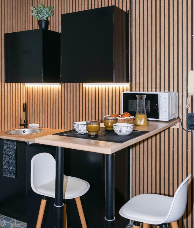 Il comprend une cuisine équipée d'une table avec deux chaises et d'un four micro-ondes. dans l'établissement Studio Confort Plus, à Limoges