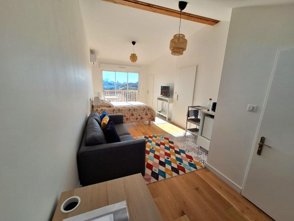 Una sala de estar con un sofá y un dormitorio. en Studio 2 rénové balcon garage, en Burdeos