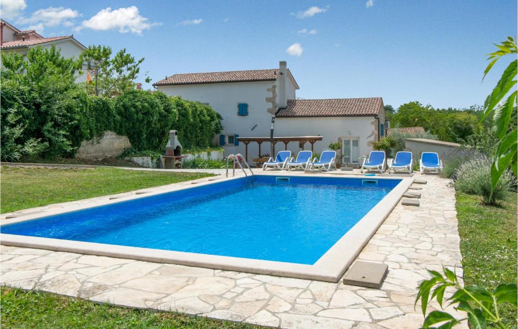 basen w podwórzu domu z niebieskimi krzesłami i dom w obiekcie 3 Bedroom Amazing Home In Ruzici w mieście Ružići