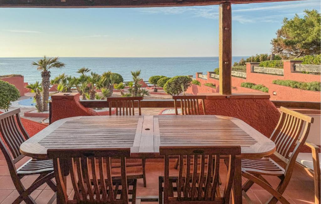 a wooden table and chairs on a patio with the ocean at 2 Bedroom Beautiful Home In Castelsardo in Castelsardo