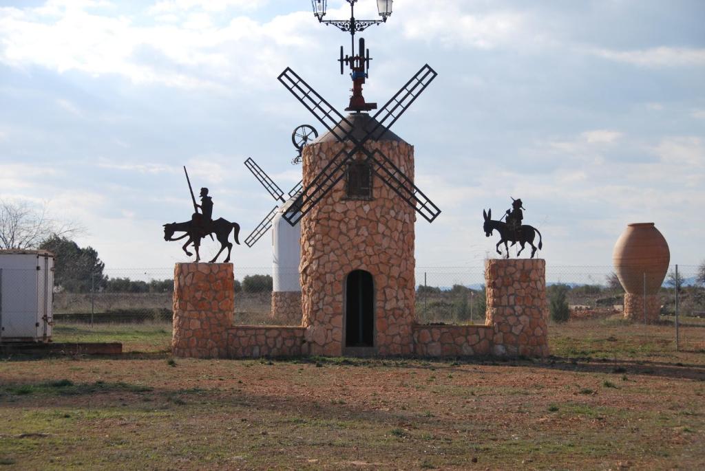 un mulino a vento in pietra con una statua di persone che cavalcano cavalli di Alojamiento Rural Los Delfines a Valdepeñas