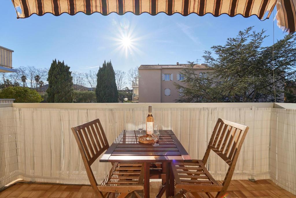 a table with two chairs and a bottle of wine at Parenthèse ensoleillée - Plage & douceur au Pradet in Le Pradet