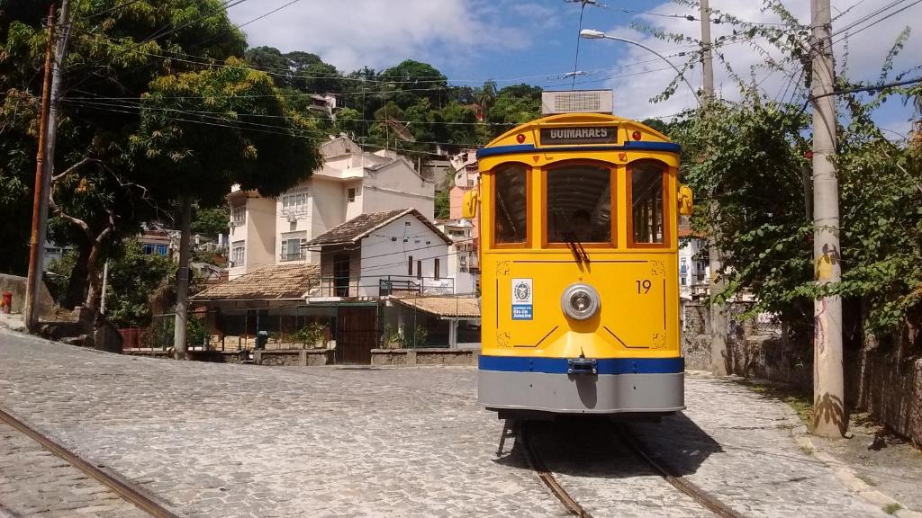 a yellow train traveling down the tracks on a street at Residencial Santa Teresa in Rio de Janeiro