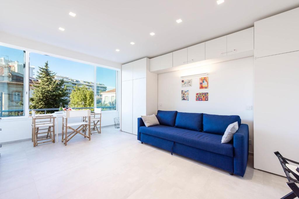 un salon avec un canapé bleu et une table dans l'établissement 1-Br Apartment Quiet Area near Cannes Center, à Cannes