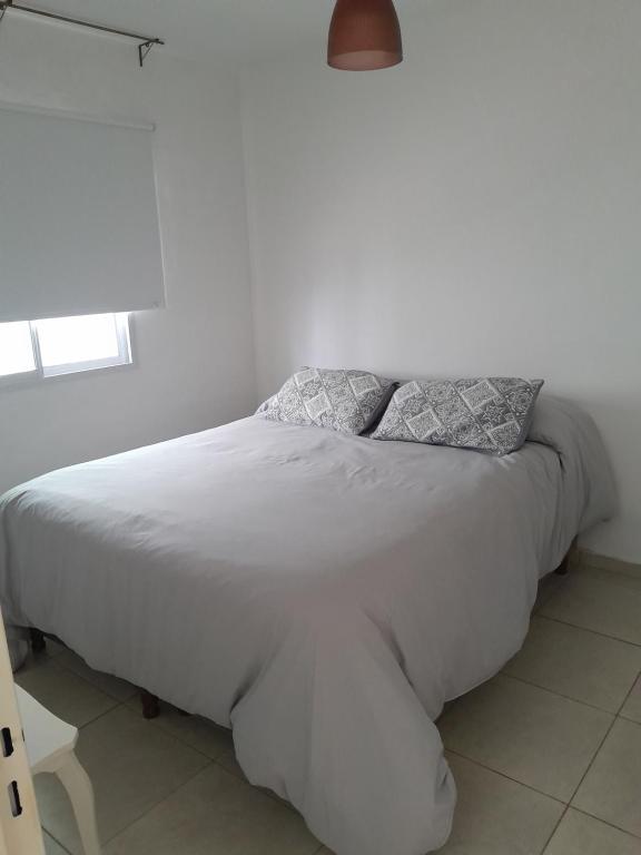 a white bed with two pillows on it in a bedroom at Departamento Rivadavia Sur in San Luis