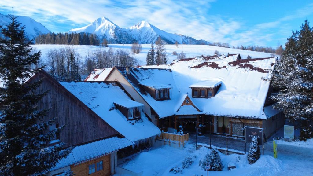 a house covered in snow with mountains in the background at SOVA Hotel&Restaurant in Ždiar