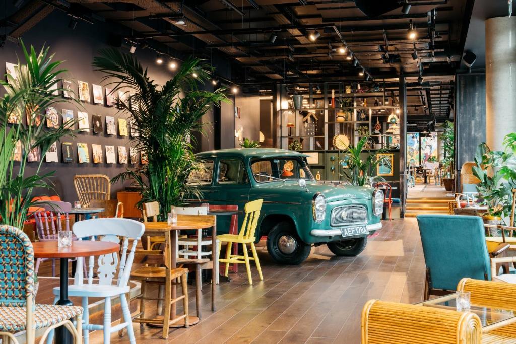 una vecchia auto parcheggiata in un ristorante con tavoli e sedie di Ruby Zoe Hotel London a Londra