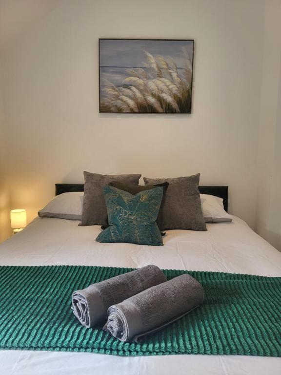 a bed with two rolled up towels on it at Parkgate Charming Cottage in Chelsfield