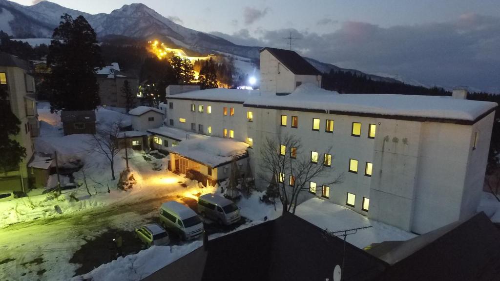 ein großes weißes Gebäude mit Schnee auf dem Boden in der Unterkunft Kogakuro in Myōkō