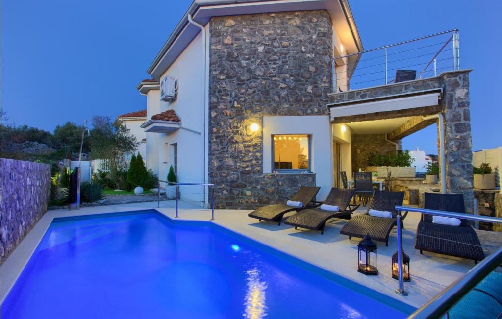a villa with a swimming pool in front of a house at Beautiful Home In Krk in Krk