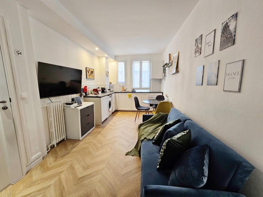a living room with a blue couch and a kitchen at Charme apt a Paris ideal for 3p in Paris