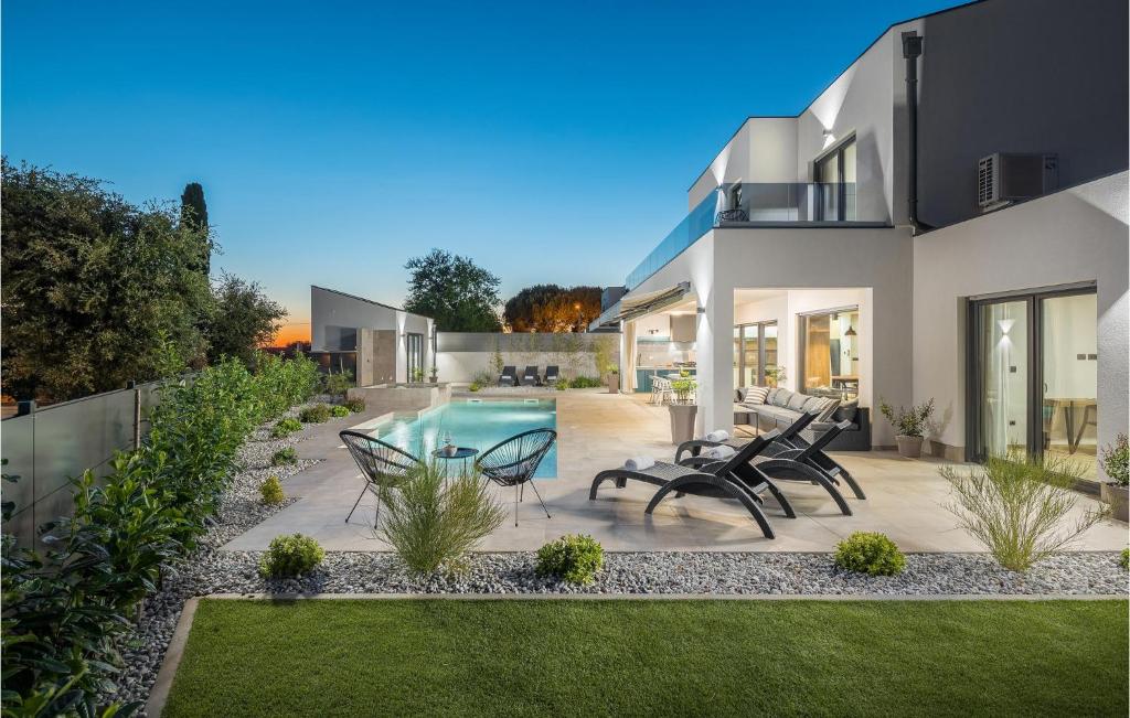 a house with a pool and chairs in the yard at 4 Bedroom Beautiful Home In Banjole in Banjole