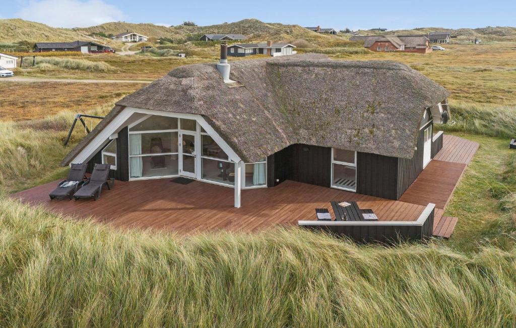 a thatch roof house with a deck in a field at Lyngbo in Havrvig