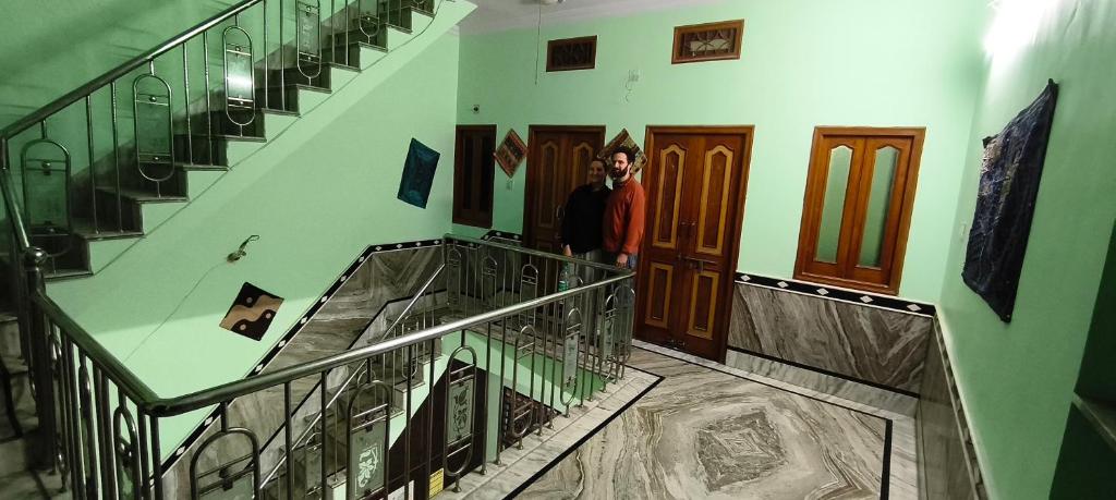 a man is standing in a hallway with stairs at Rose Merry Guesthouse in Bikaner