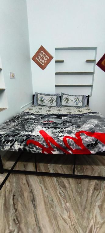 a bedroom with a bed with a black and red comforter at Rose Merry Guesthouse in Bikaner