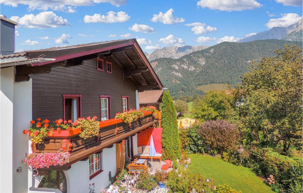 dom z kwiatami na balkonie z górami w tle w obiekcie Gemuetliche Ferienwohnung w mieście Saalfelden am Steinernen Meer