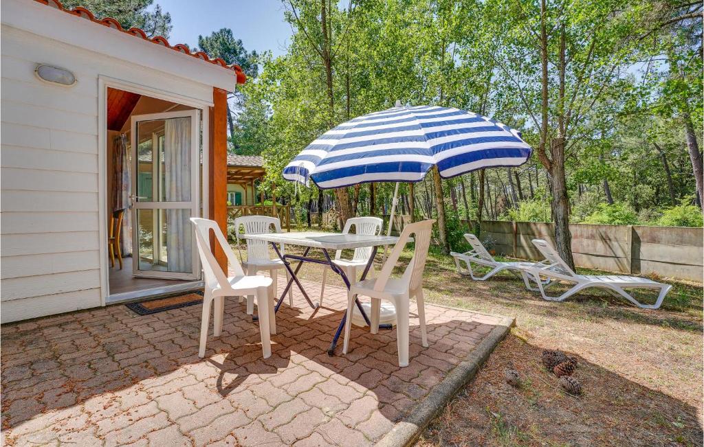 a table and chairs and an umbrella on a patio at Cozy Home In La Faute-Sur-Mer in La Faute-sur-Mer