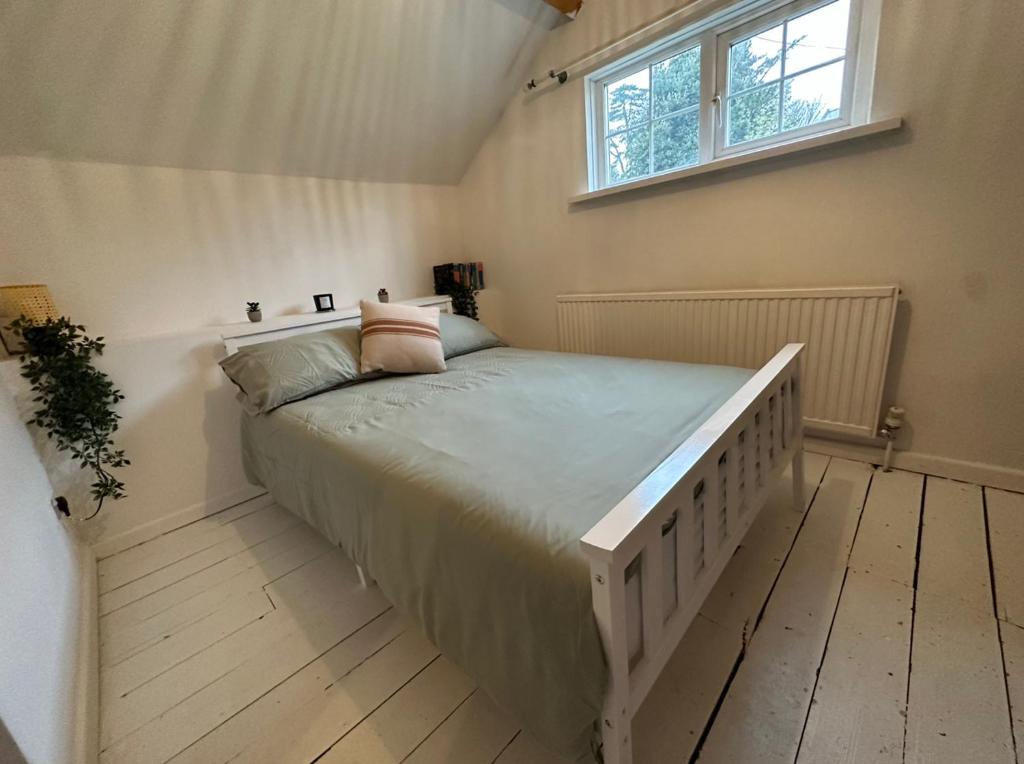 a bedroom with a large bed with a window at Cosy Cottage 7 mins from Cardiff City Center in Cardiff