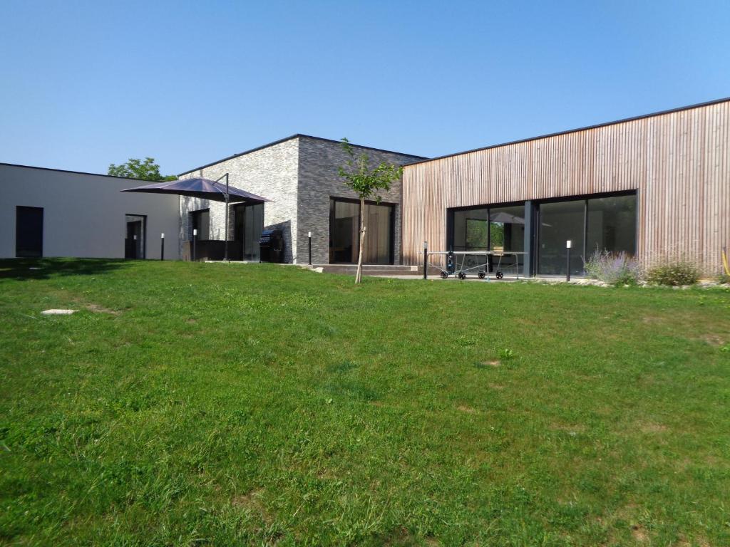 une maison avec une pelouse verte devant elle dans l'établissement Villa La Bertine Haute, à Saillac