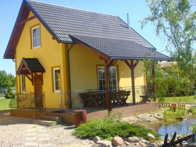 a small yellow house with a porch and a roof at Sun Village Domki in Stegna
