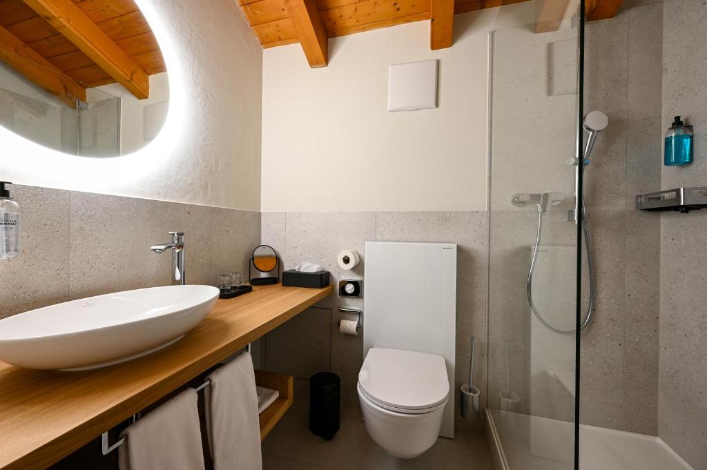 a bathroom with a sink and a toilet and a shower at Hotel Sonnwendhof Engelberg in Engelberg