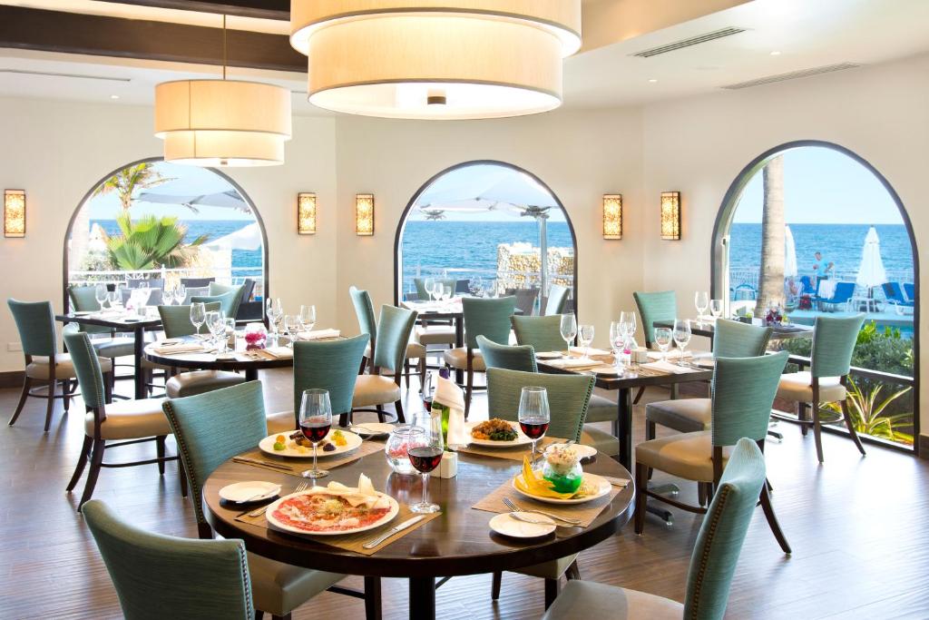a restaurant with tables and chairs with the ocean in the background at Oyster Bay Beach Resort in Dawn Beach