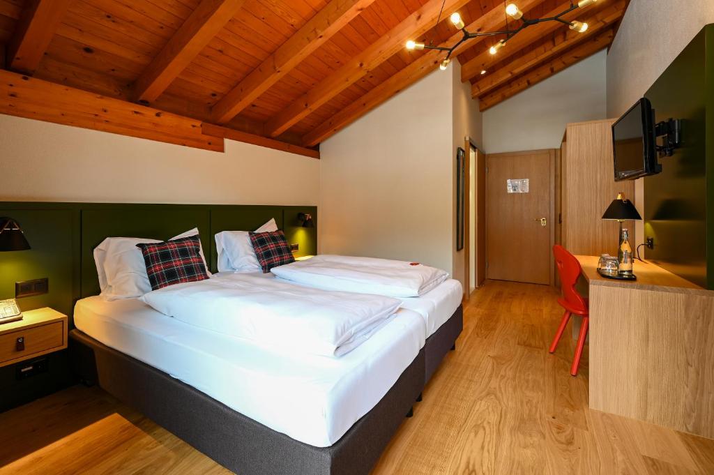 a bedroom with a large bed and a desk at Hotel Sonnwendhof Engelberg in Engelberg
