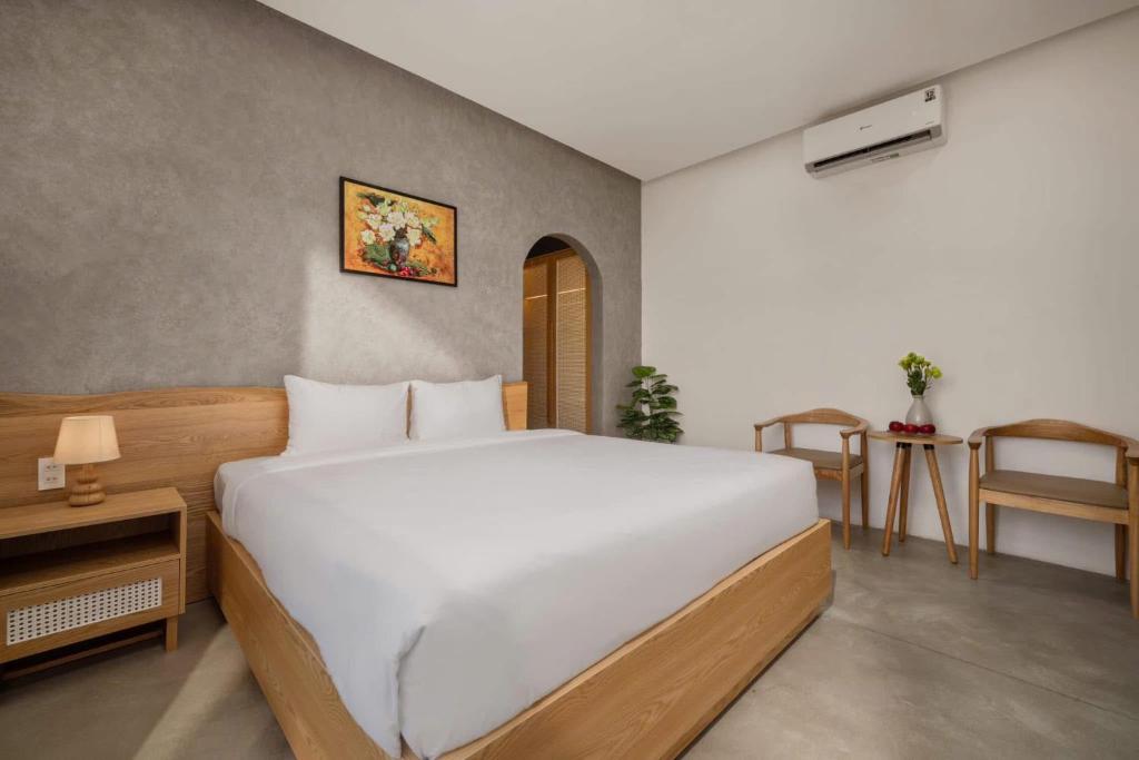 a bedroom with a large white bed and a table at MAY HOMESTAY Villa in Hue