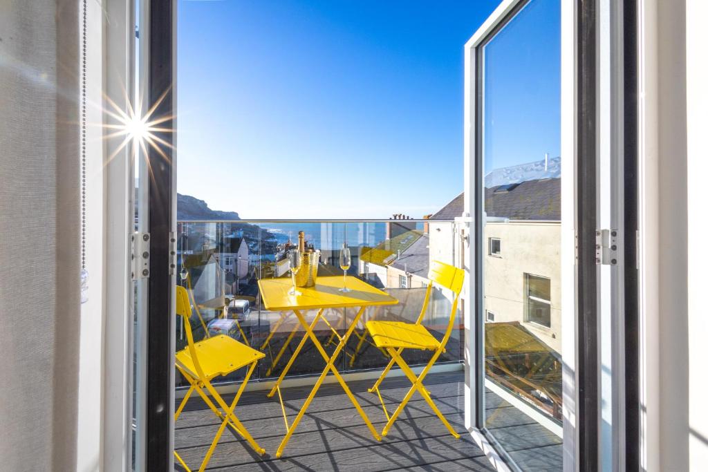 a balcony with yellow chairs and a table on a balcony at Bright & beautiful 4 bedroom house with sea views in Portland