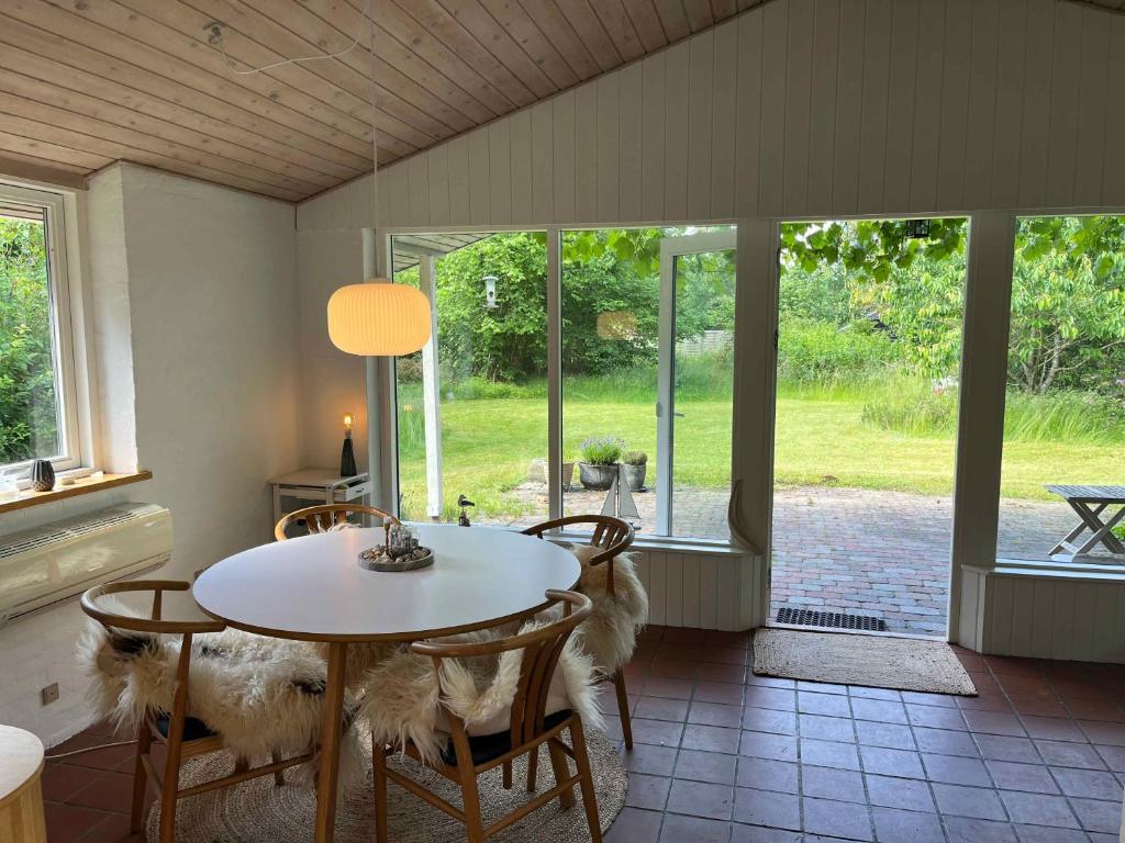 a dining room with a table and chairs and windows at Cosy Summer Cottage Glose To Sandy Beach! in Knebel
