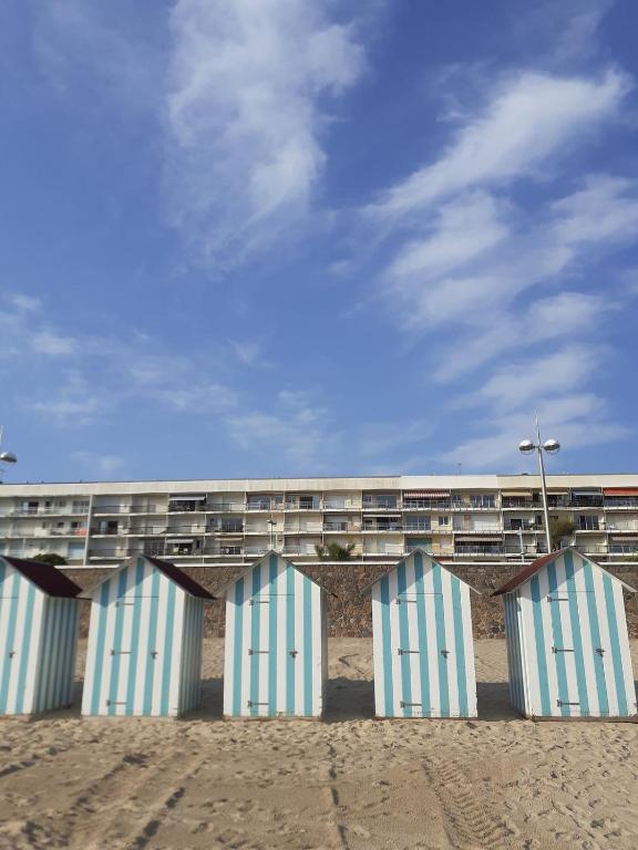 Une rangée de bâtiments bleus et blancs sur la plage dans l'établissement Appartement face mer Rêve de Flo ts, à Saint-Jean-de-Monts