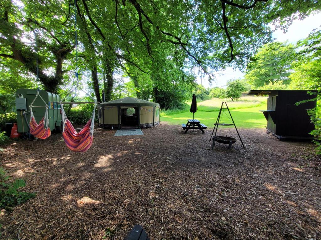a camp site with a hammock and a tent at Cosy Glamping Yurt with log burner on our smallholding, ideal family getaway or romantic retreat in Narberth