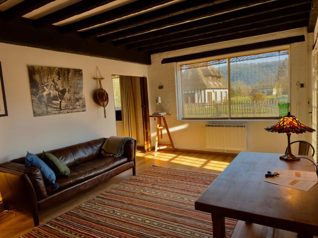 a living room with a leather couch and a table at La Forge Tranquille in Heudreville-sur-Eure